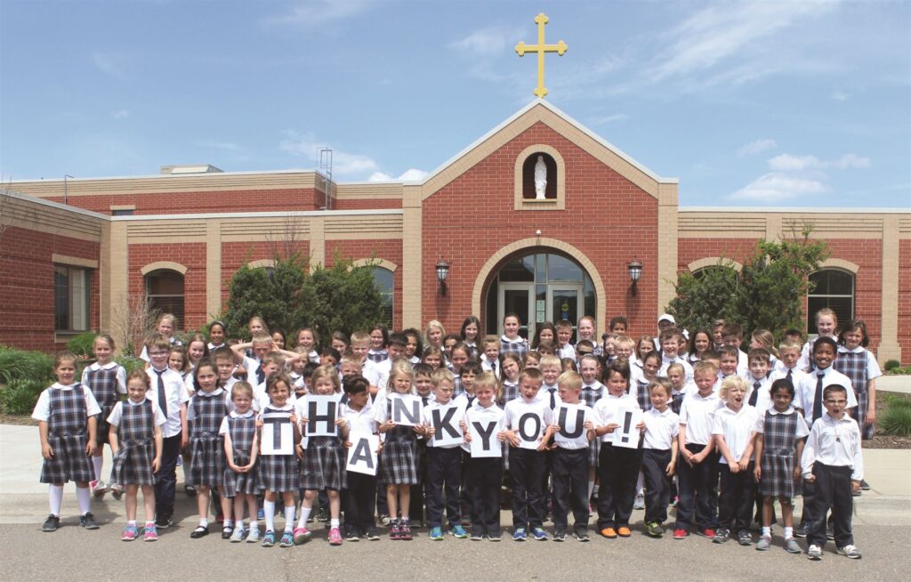 Students lining up in front of school with sign saying thank you